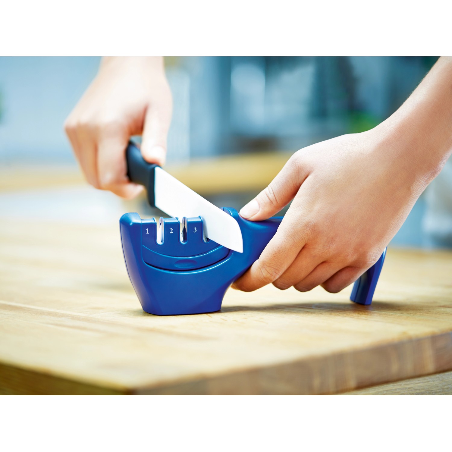 LUX Messerschärfer in Aktion: Messer wird durch die Schärfvorrichtung gezogen.