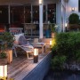 Philips Hue Impress Wegeleuchte: Schwarze LED Außenleuchte auf Terrasse mit Teich und Fischen.