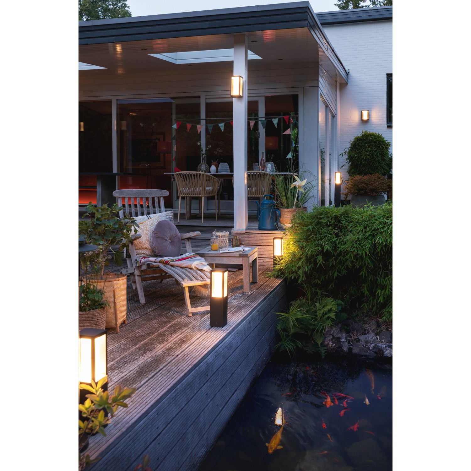 Philips Hue Impress Wegeleuchte: Schwarze LED Außenleuchte auf Terrasse mit Teich und Fischen.