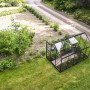 Schwarzes Halls Gewächshaus Popular 6,2 m² im Garten, mit Pflanzen und geöffneten Dachfenstern.
