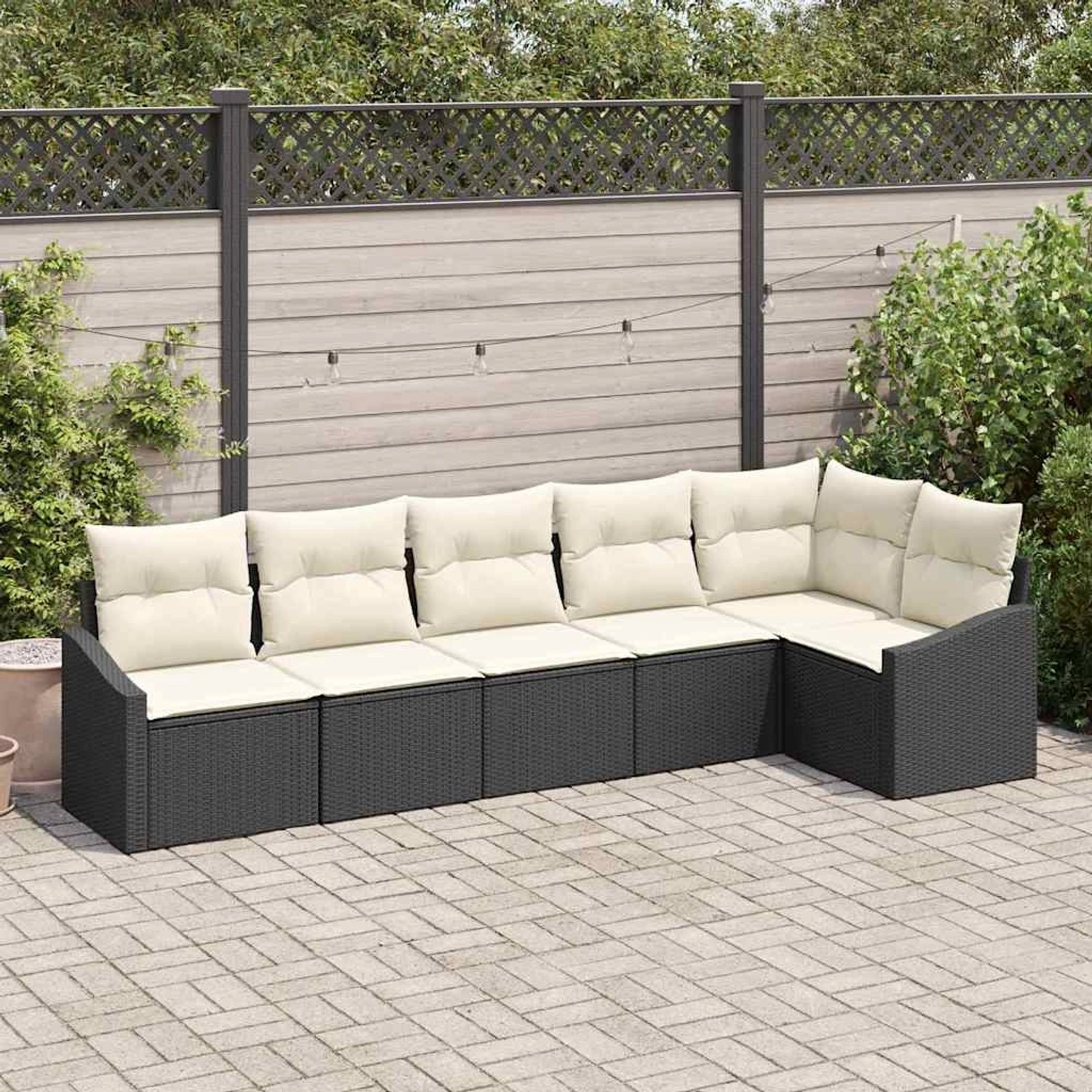 Schwarzes 6-teiliges vidaXL Garten-Sofa-Set aus Poly Rattan mit beigen Kissen vor Holzwand.