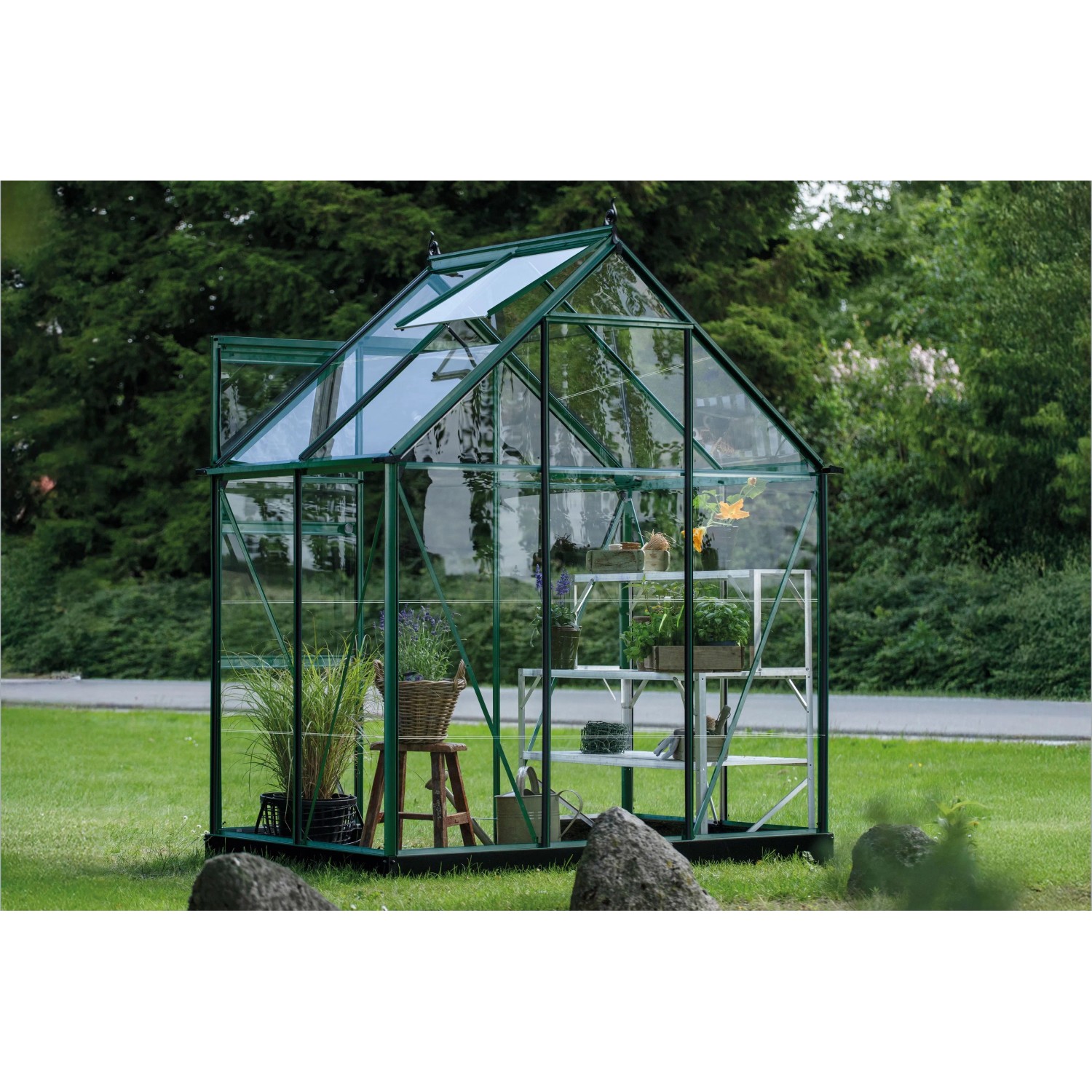 Grünes Halls Gewächshaus Icon 6 mit Glas und Regalen im Garten.