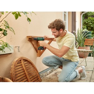 Mann schraubt Holzregal mit Bosch EasyImpact 18V-38 Akku-Kombibohrer an Wand.