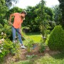 Frau nutzt Gardena combisystem-Teleskopstiel im Garten zur Gartenarbeit.
