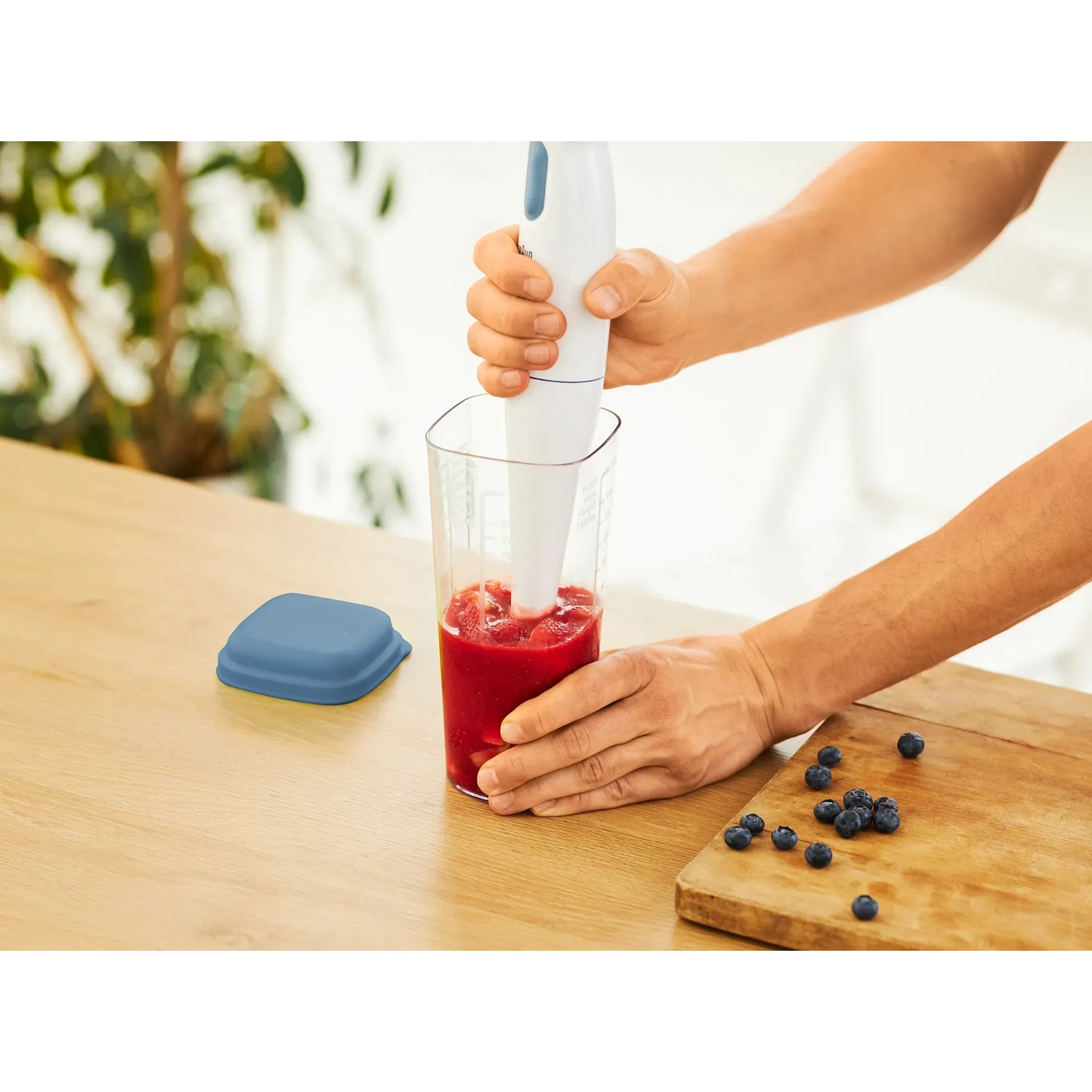 Rotho Küchenhelfer Loft: 5-in-1 Messbecher transparent mit Horizontblau Deckel und Stabmixer in Nutzung.