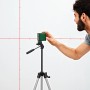 Bosch Quigo Plus Kreuzlinienlaser mit Stativ und Markierungen an Laserlinien im Einsatz.