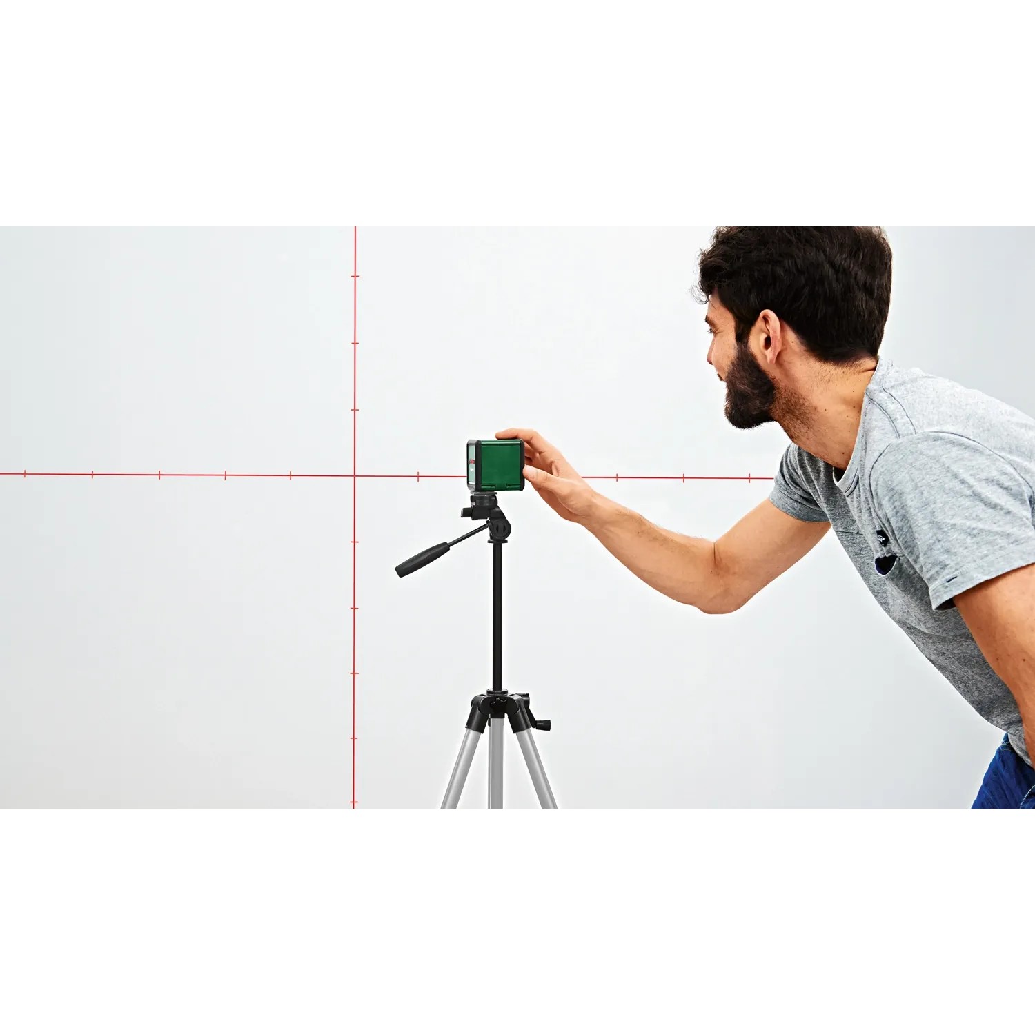 Bosch Quigo Plus Kreuzlinienlaser mit Stativ und Markierungen an Laserlinien im Einsatz.