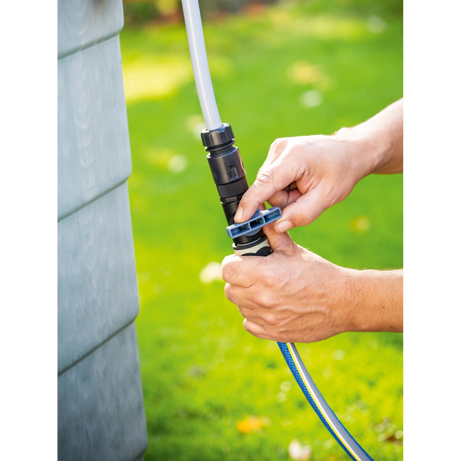 Anschluss eines Gartenschlauchs an eine Akku-Regenfasspumpe am Regenfass.