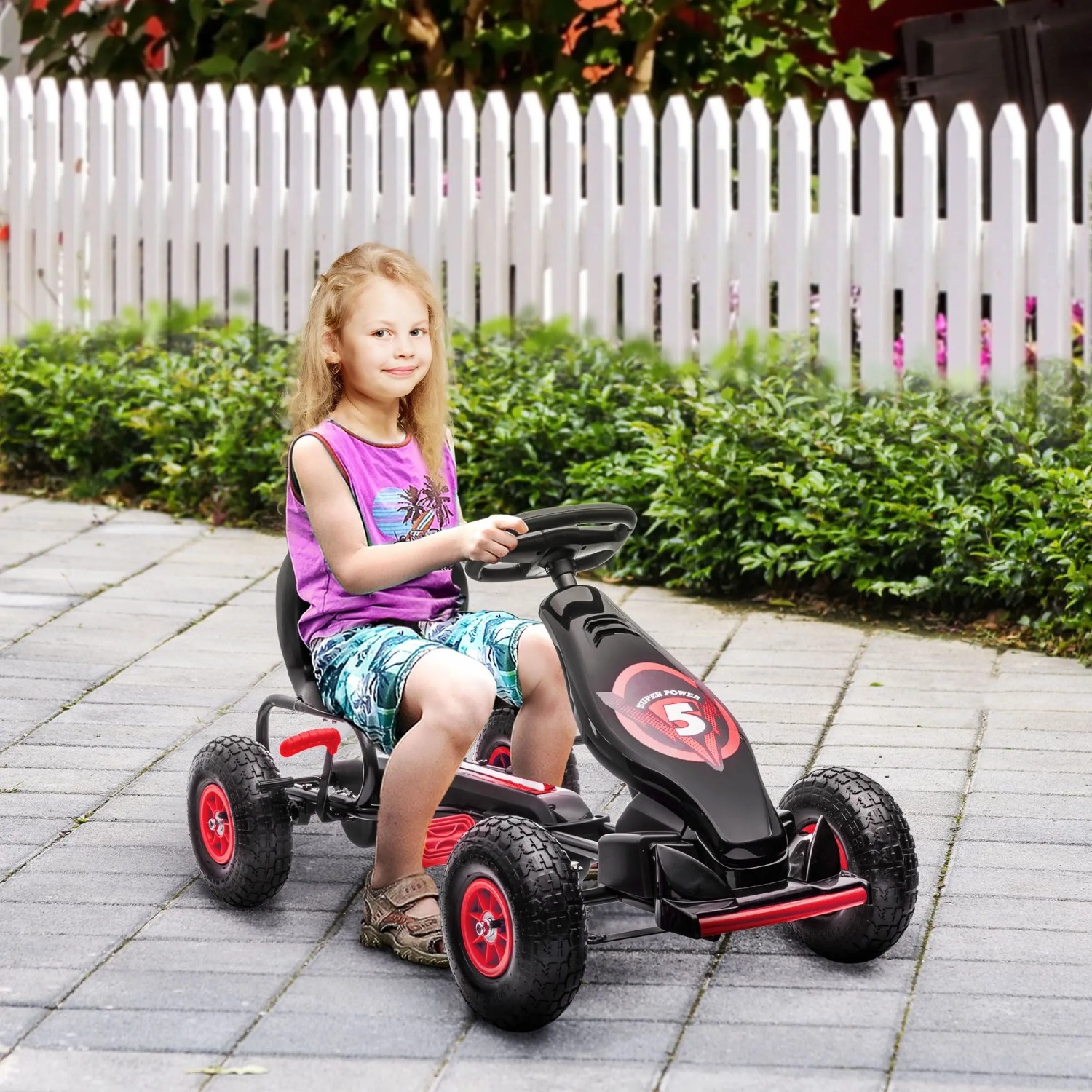 Mädchen fährt schwarzes HOMCOM Gokart mit roten Akzenten, verstellbarem Sitz und Gummireifen auf gepflastertem Weg.