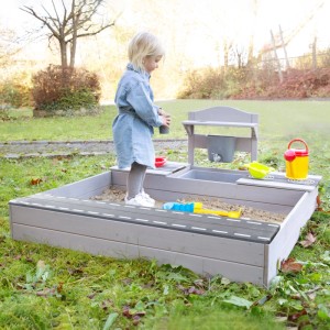 Grauer roba Sandkasten mit Matschküche aus FSC-Holz und spielendem Kind im Garten.