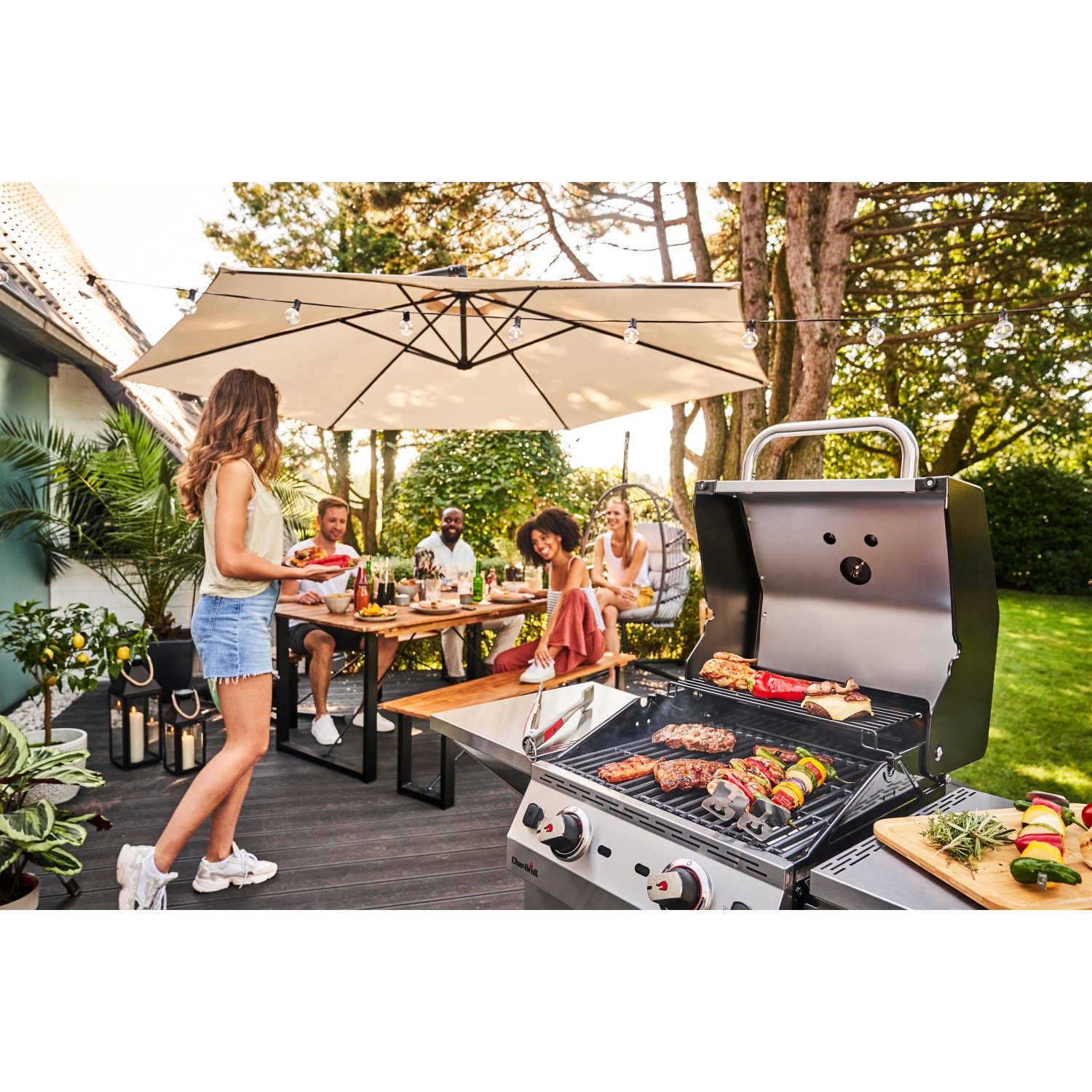 Char-Broil Gasgrill Performance PRO S 2 beim Grillen mit Freunden im Garten.