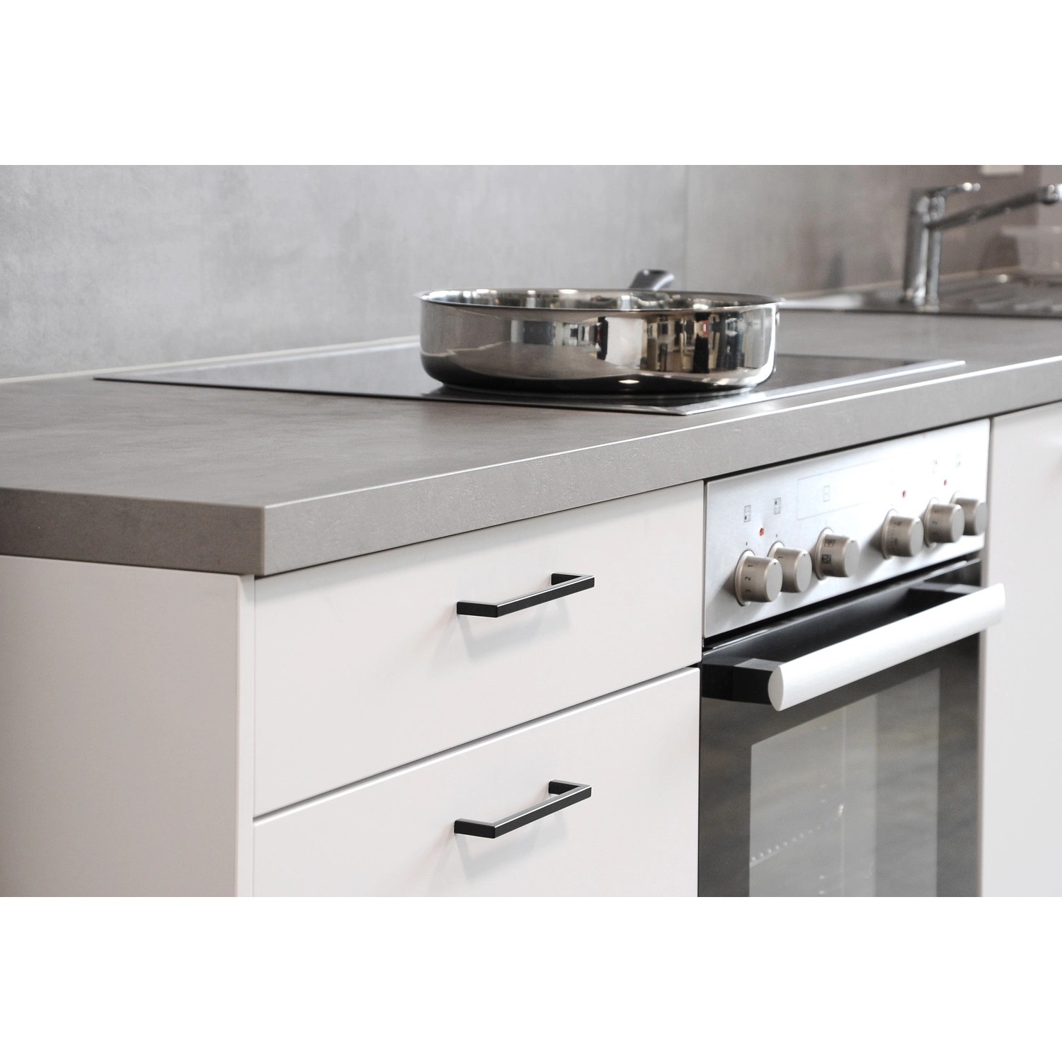 Schwarzer, matter Siro Möbelgriff 2108 an weißen Küchenschränken mit Lochabstand 128 mm.