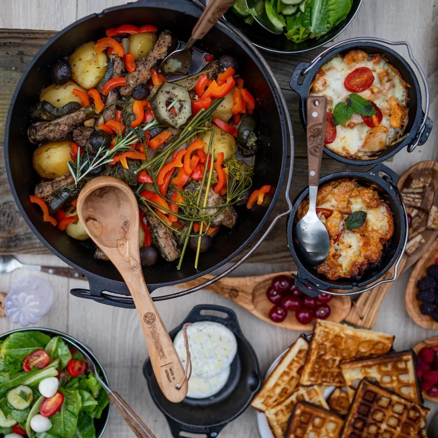 Petromax Dutch Oven FT4.5-T mit Speisen und Beilagen, ideal für Outdoor-Küche und Grillen.