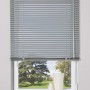 Silberne Aluminium Jalousie Burgos, 140x160 cm, am Fenster mit Ausblick ins Grüne.