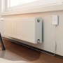 Shelly Wassersensor Flood Gen4: Sensor neben Heizkörper mit Wasserleckage auf Parkettboden.