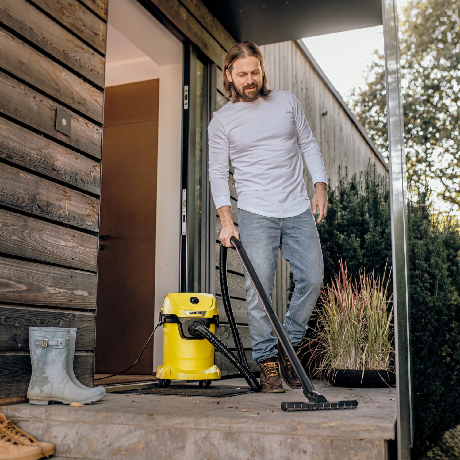 Mann saugt mit gelbem Kärcher WD 3 V-17/4/20 Nass-Trockensauger eine Terrasse.