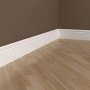 Weiße PROFHOME Sockelleisten aus Polyurethan (32 m Set) an einer braunen Wand und hellem Holzboden.