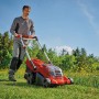 Einhell Akku-Rasenmäher GP-CM 36/450 im Einsatz: Mann mäht Rasen mit dem roten Akkumäher.