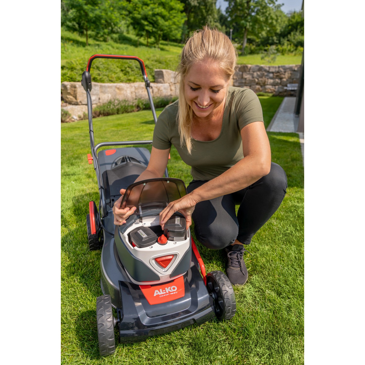 Frau setzt Akku in Al-Ko Akku-Rasenmäher 42.2 Li Comfort. Inkl. Akku und Ladegerät.