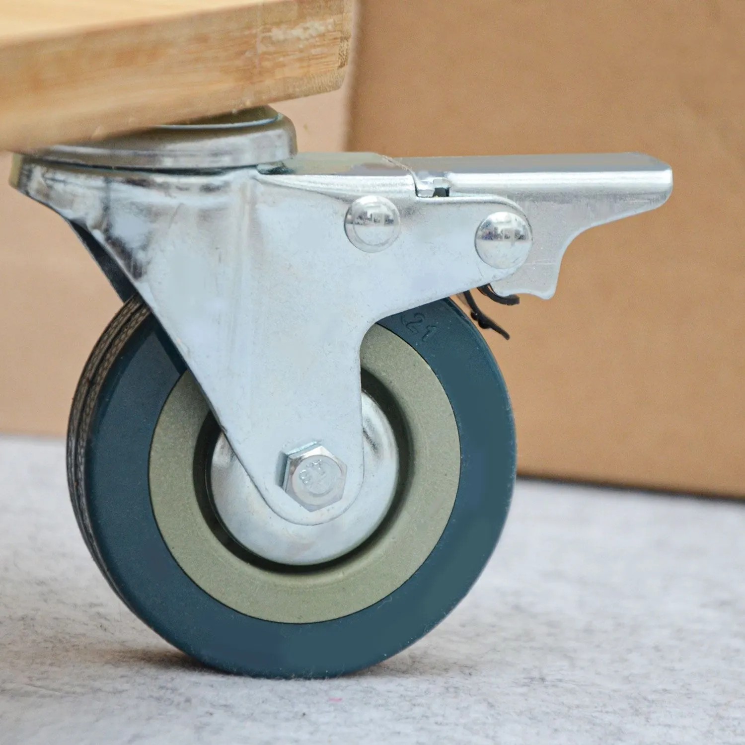 Schwerlast Möbelrolle 75 mm mit Bremse, verzinkter Stahl, Nylonrad, unter Holzplatte montiert.