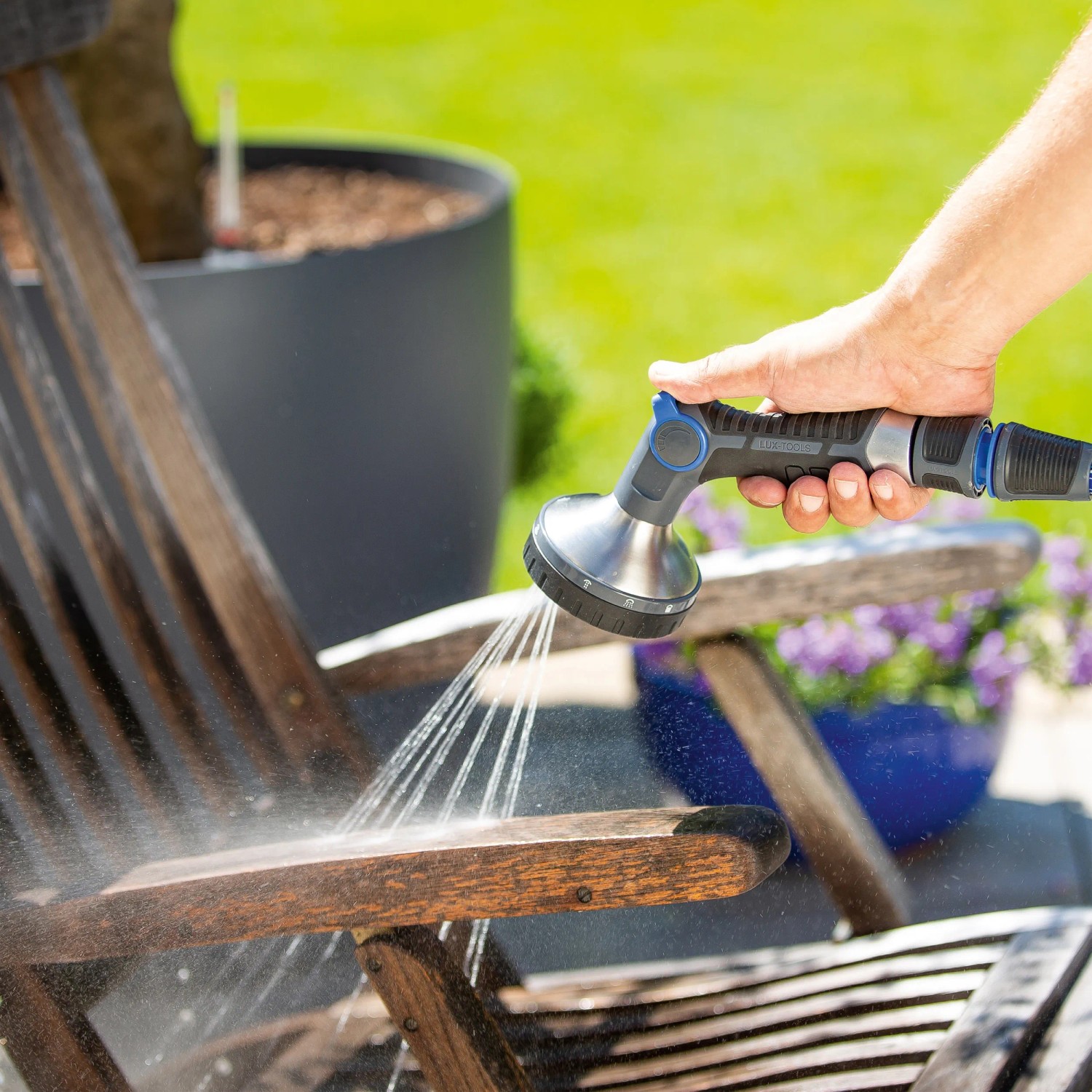 LUX Multifunktionsbrause mit 10 Strahlvarianten beim Reinigen eines Gartenstuhls.