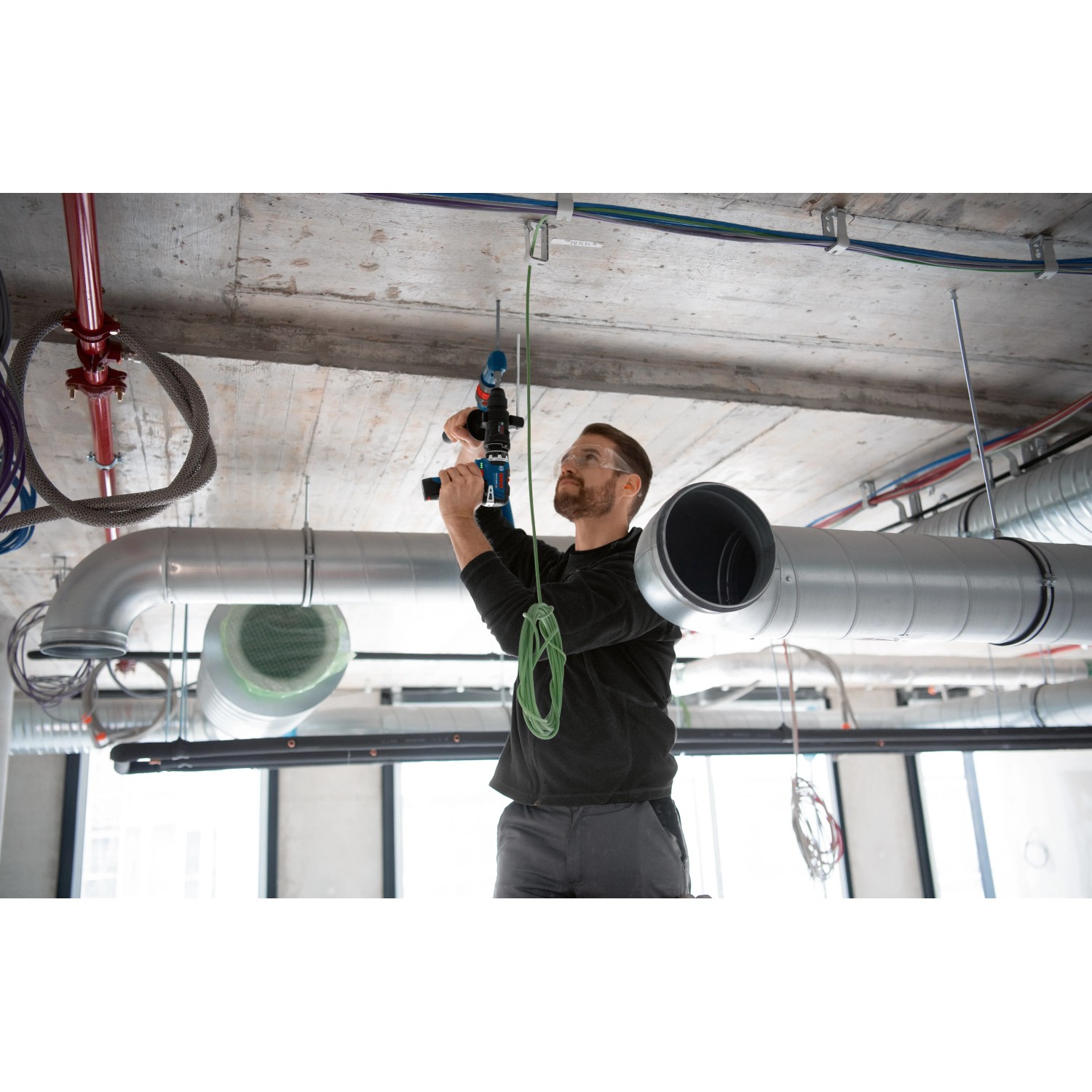 Mann bohrt mit Bosch Professional GFA 12-H FlexiClick Bohrhammeraufsatz in Decke.