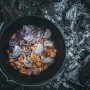Petromax Dutch Oven Set FT9-T-Scrub: Gusseisen-Topf mit Zwiebeln und Kartoffeln über offenem Feuer.