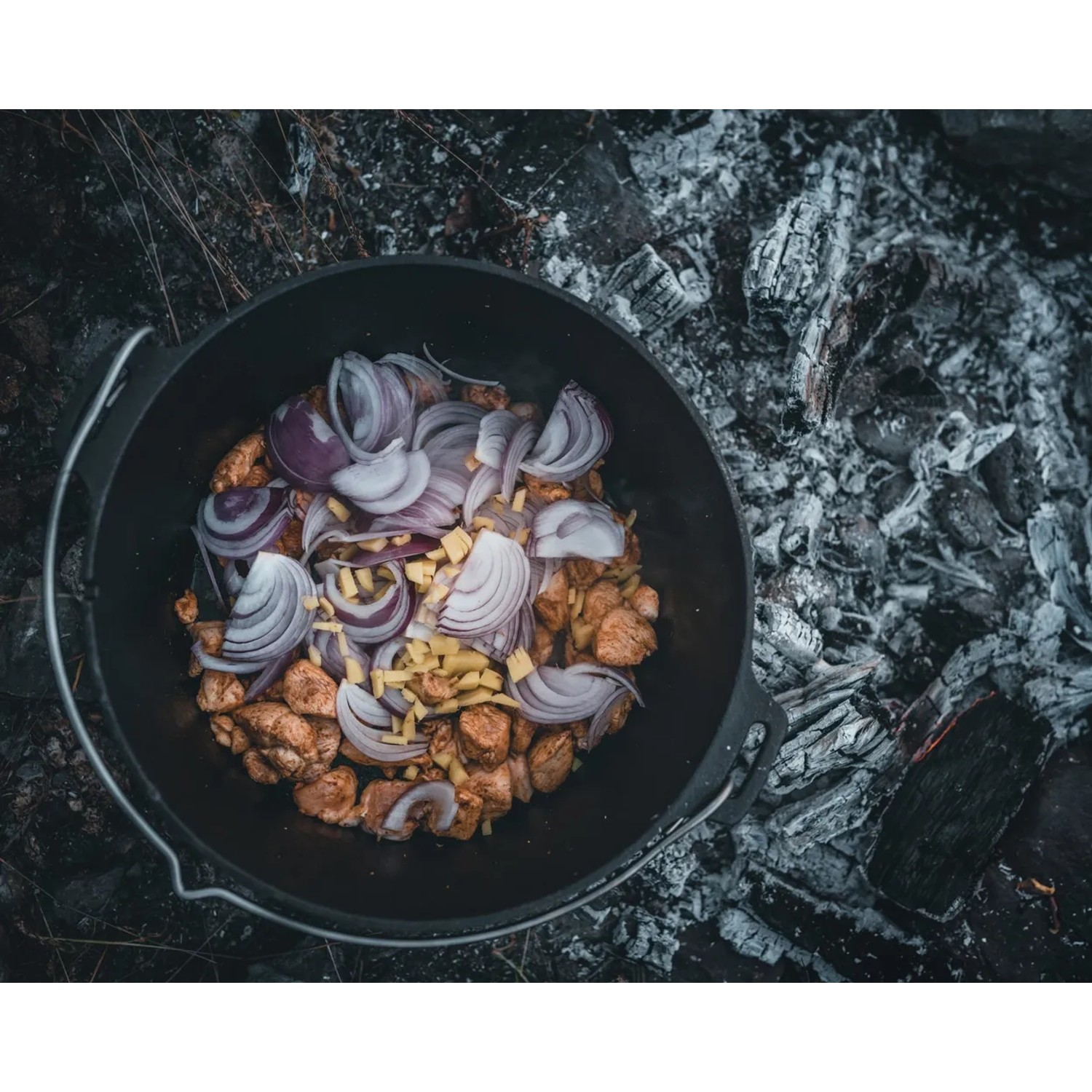 Petromax Dutch Oven Set FT9-T-Scrub: Gusseisen-Topf mit Zwiebeln und Kartoffeln über offenem Feuer.