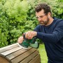 Mann schleift Holz mit dem Bosch Akku-Exzenterschleifer UniversalOrbit 18V-20. Schleifmaschine für Heimwerker.