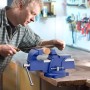 Mann feilt Holzstück in blauem Wiltec Schraubstock auf Werkbank. 100mm Klemmbacke, Amboss, Spannwerkzeug.