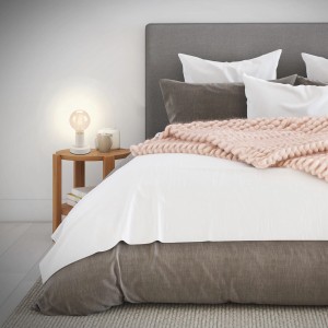 Weiße Brilo Tischleuchte Teepu mit E27 Fassung auf Nachttisch neben Bett.