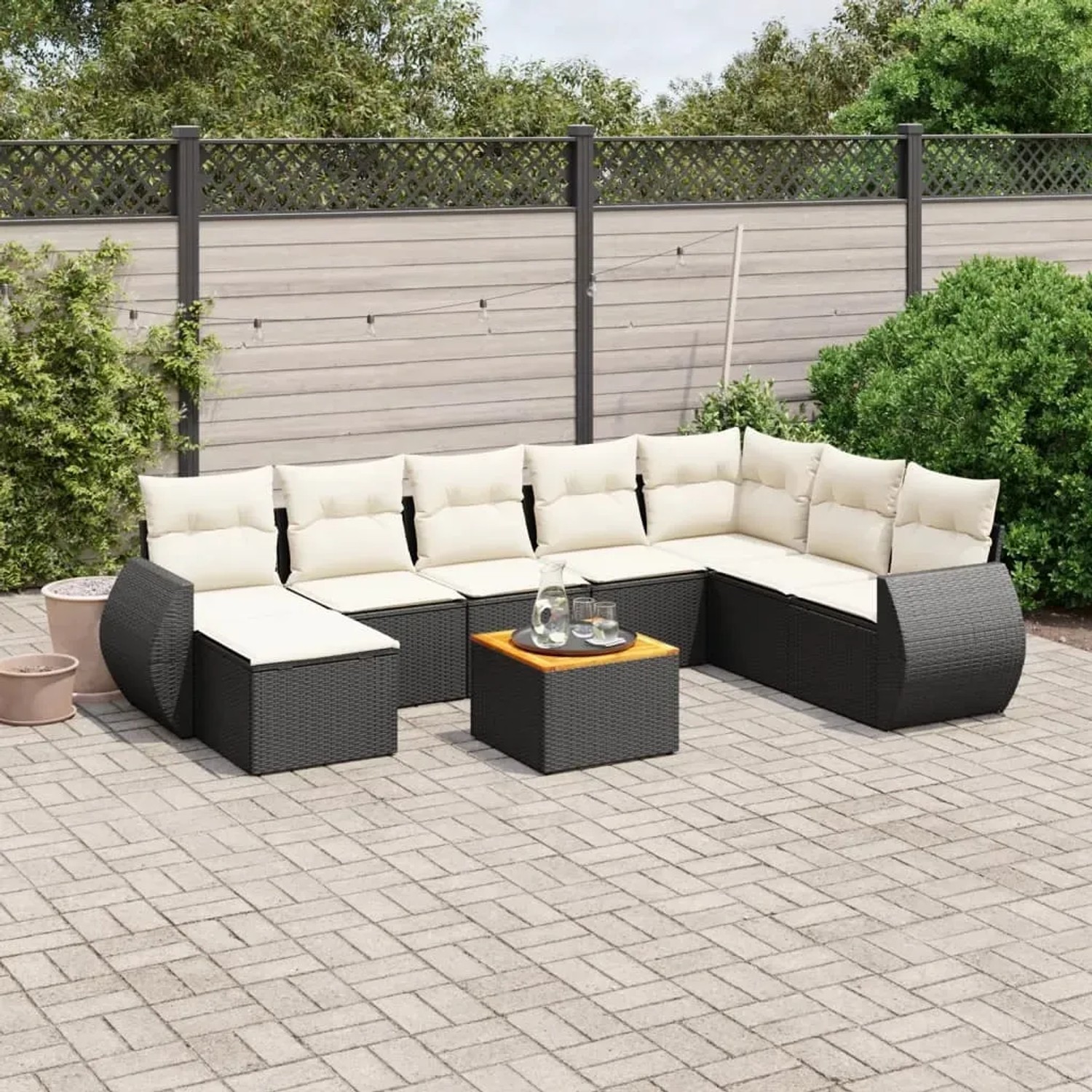 Schwarze 9-teilige Garten-Sofagarnitur aus Polyrattan mit cremefarbenen Kissen und Akazientisch.
