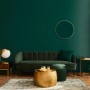 Wohnzimmer-Szene mit DSK Design-Wandspiegel Picasso, Ø 60 cm, Gold, über einem grünen Sofa.