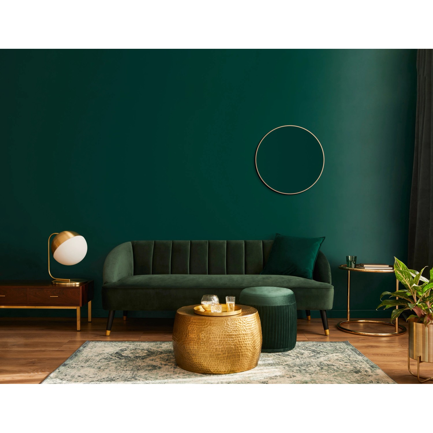 Wohnzimmer-Szene mit DSK Design-Wandspiegel Picasso, Ø 60 cm, Gold, über einem grünen Sofa.