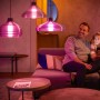 Szene mit Philips Hue Leuchten: Vater und Tochter auf Sofa unter smarten Hängelampen.