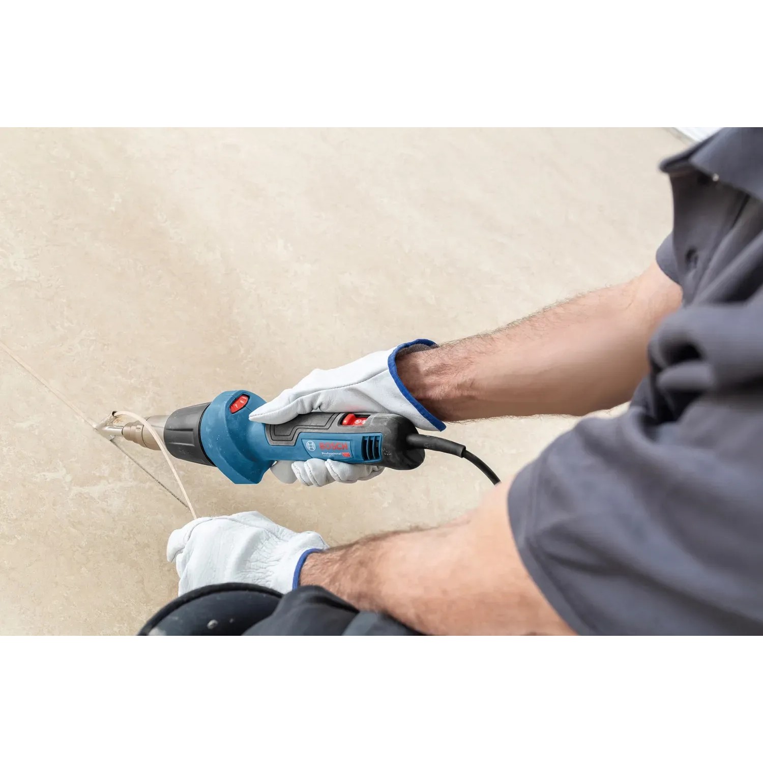 Bosch Professional Heißluftgebläse GHG 20-60 im Einsatz, blau, mit Düse und Handschuhen.