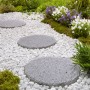 Naturstein-Trittsteine Sino Grau, Ø 25 cm, im Gartenweg mit weißen Zierkieseln.