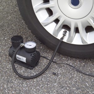 Schwarzer Kompressor mit Manometer pumpt Autoreifen auf. Autoreparatur Zubehör.