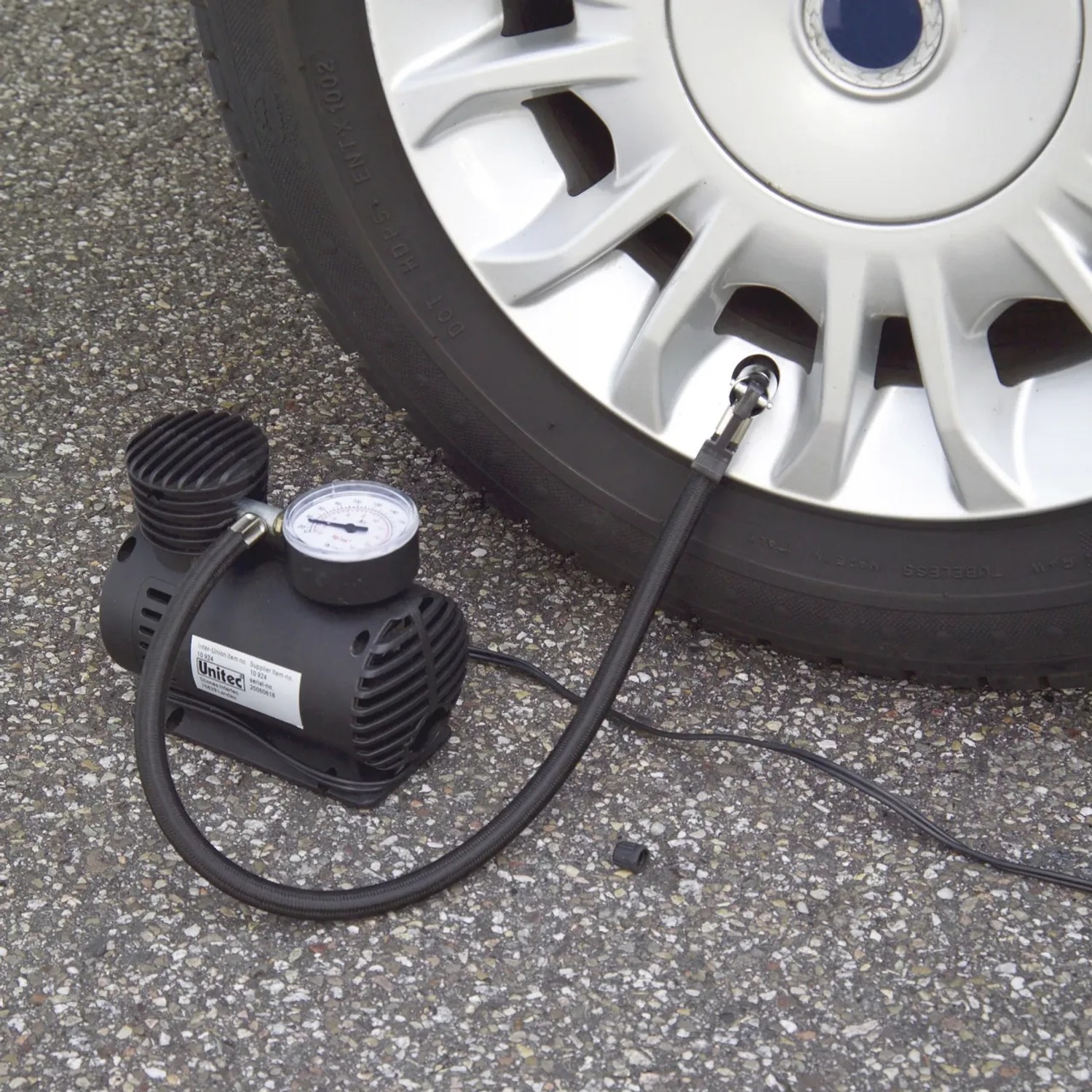 Schwarzer Kompressor mit Manometer pumpt Autoreifen auf. Autoreparatur Zubehör.
