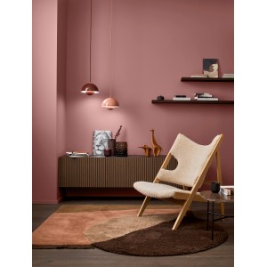 Raum in Rharbarberrot mit Alpina Wandfarbe, Sessel und Teppich in Braun- und Beigetönen.