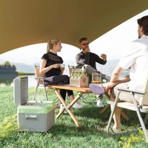 Grau-grüne Outsunny Kühlbox offen im Gras, daneben sitzen Freunde beim Camping am See. Ideal für Autozubehör & Reisen.
