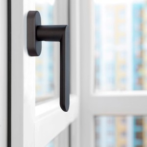 SOTECH Fenstergriff SAM, anthrazitfarben, mit Befestigungsmaterial an weißem Fenster.