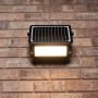 Schwarze LED Solar-Außenleuchte mit Sensor an Backsteinwand. Flutlicht mit 10W und 1.080 Lumen.