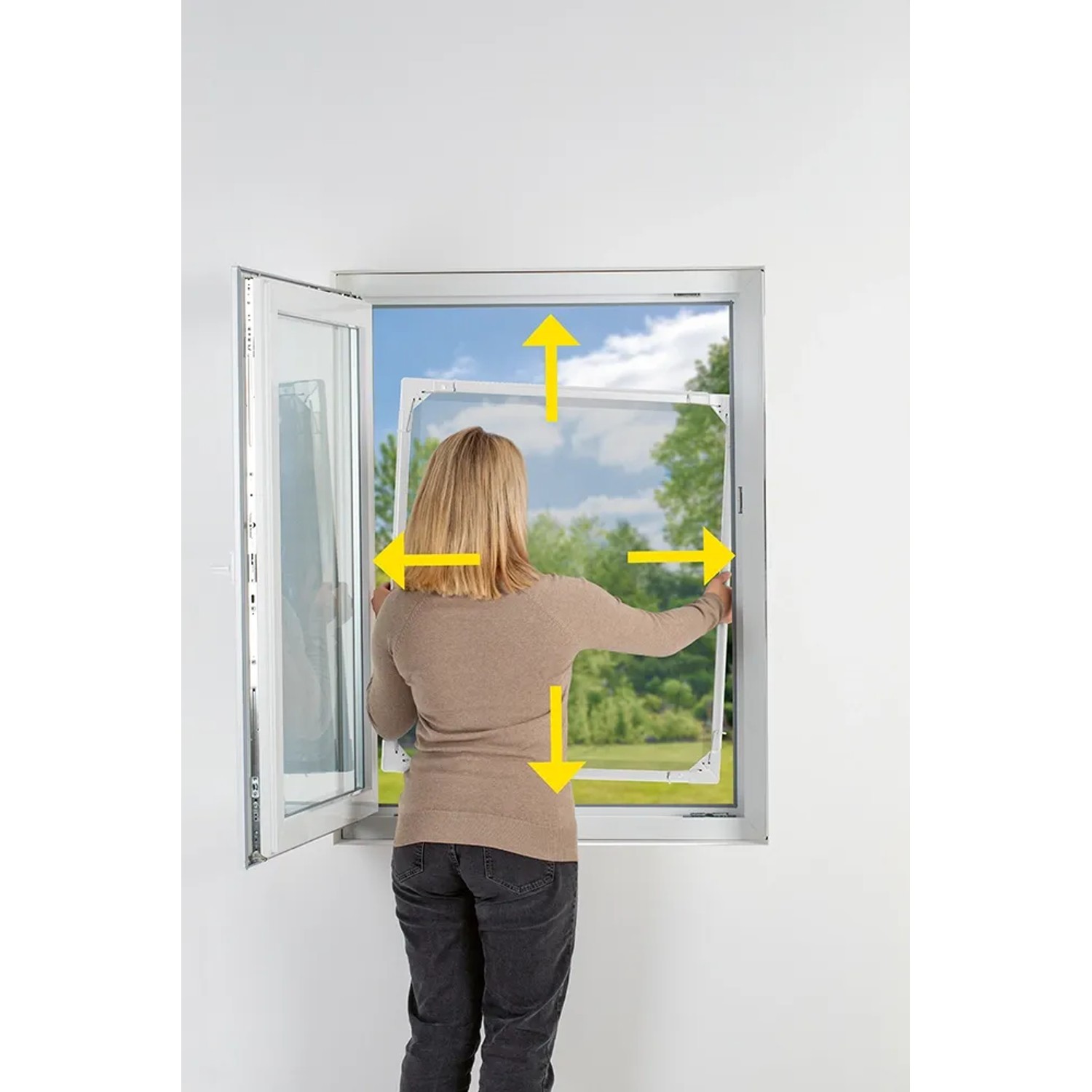Frau montiert Easymaxx Moskitonetz Magic Fit am Fenster. Insektenschutzrahmen in Weiß.