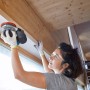 Frau schleift Holz mit Bosch Professional Akku-Exzenterschleifer GEX 18V-125. Schleifmaschine mit Schleifblatt.