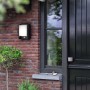 Anthrazitfarbene LED-Wandleuchte Arbour mit Sensor an einer Backsteinwand.