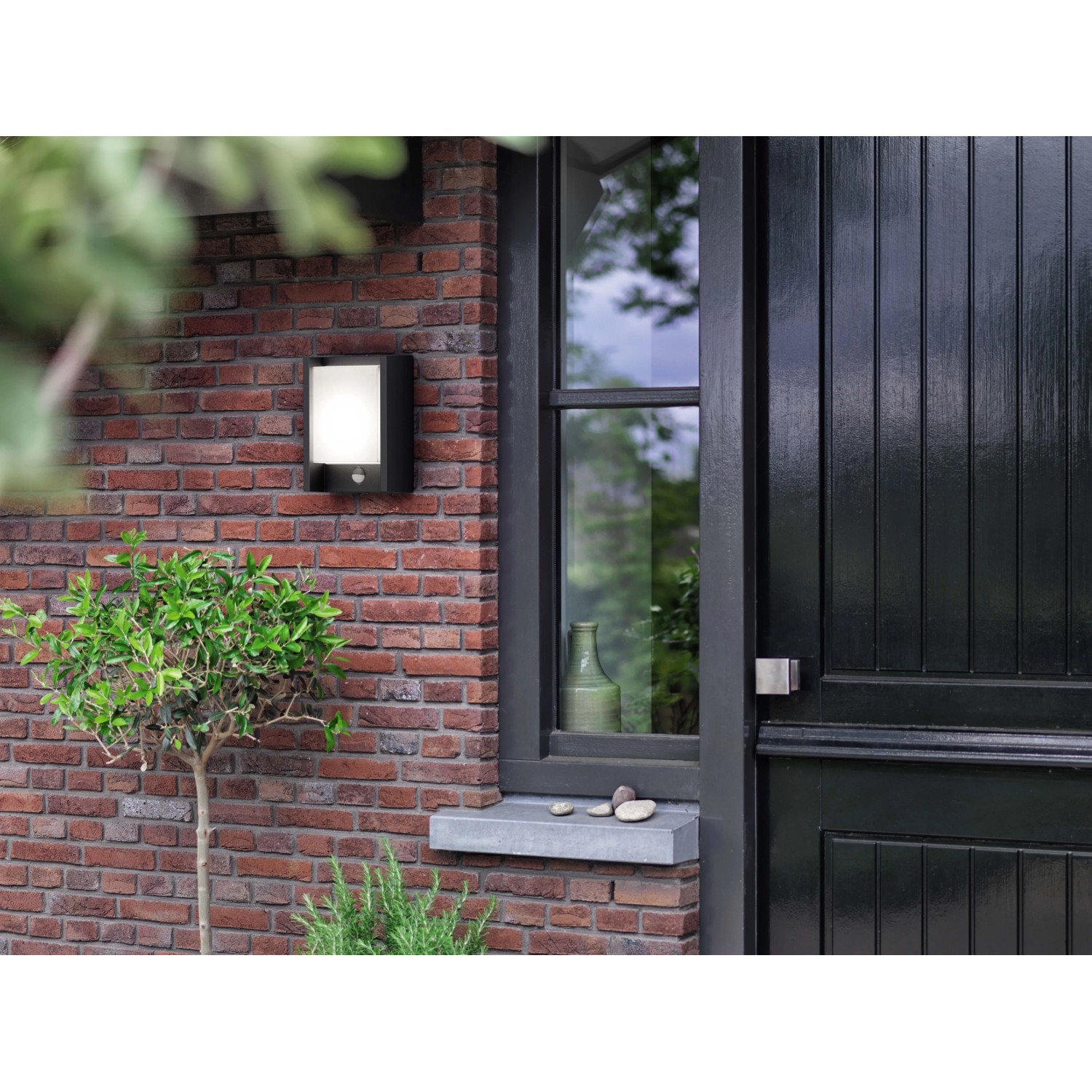 Anthrazitfarbene LED-Wandleuchte Arbour mit Sensor an einer Backsteinwand.