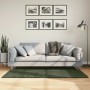 Waldgrüner Kurzflor Teppich HUARTE 80x150 cm im Wohnzimmer vor hellem Sofa. Weich, waschbar.