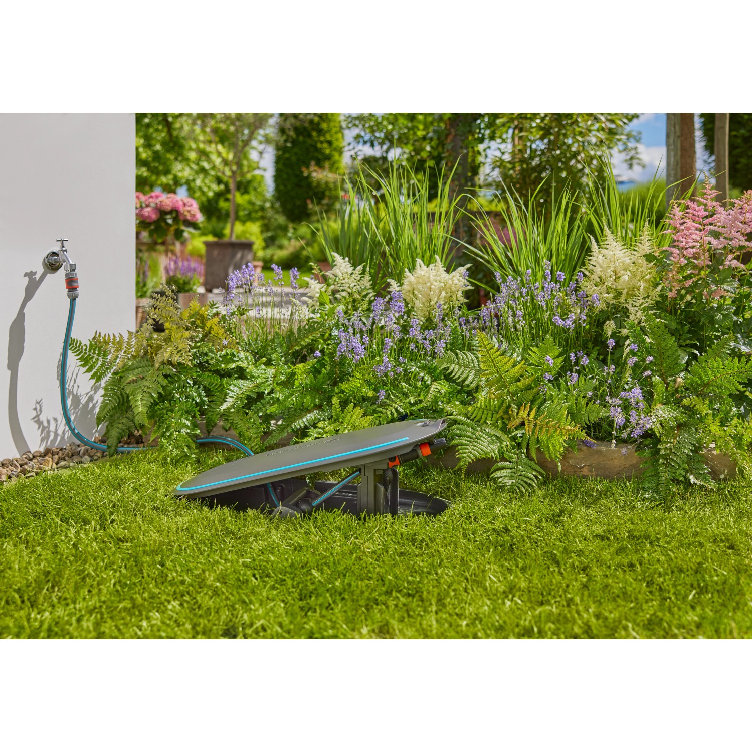 Gardena Undercover Schlauchbox RollUp M im Garten mit angeschlossenem Gartenschlauch.