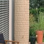 Arves Regentonne Arcado 460 l in Sandstein-Optik mit Wasserhahn im Garten.